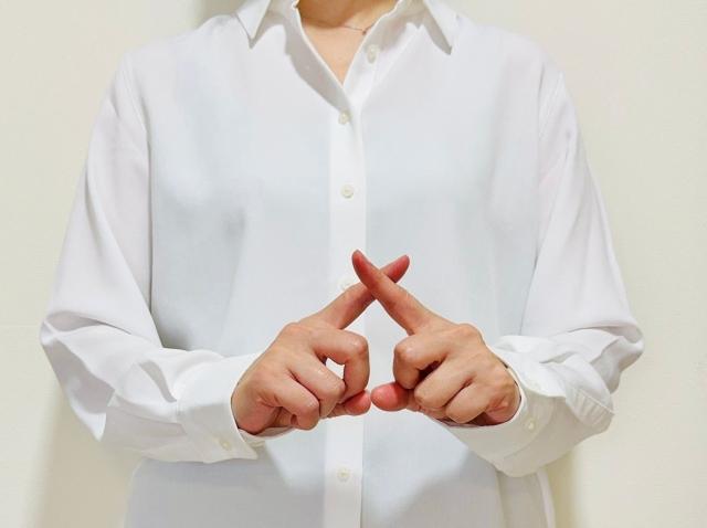 指で×を示す人の画像